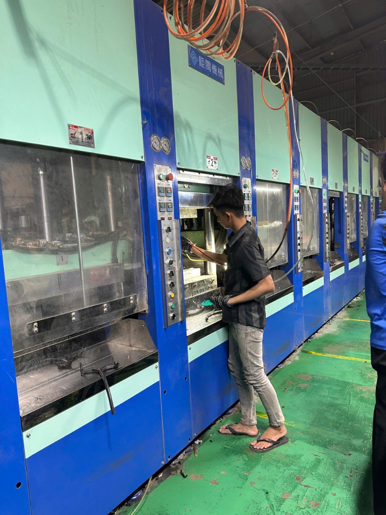 Thợ xưởng thao tác dập logo và lắp ráp quai dép